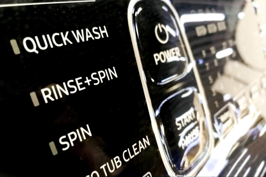 Person pressing the quick wash setting on a washing machine