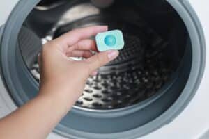 Woman Putting Water Softener Tablet Into Washing Machine Closeup