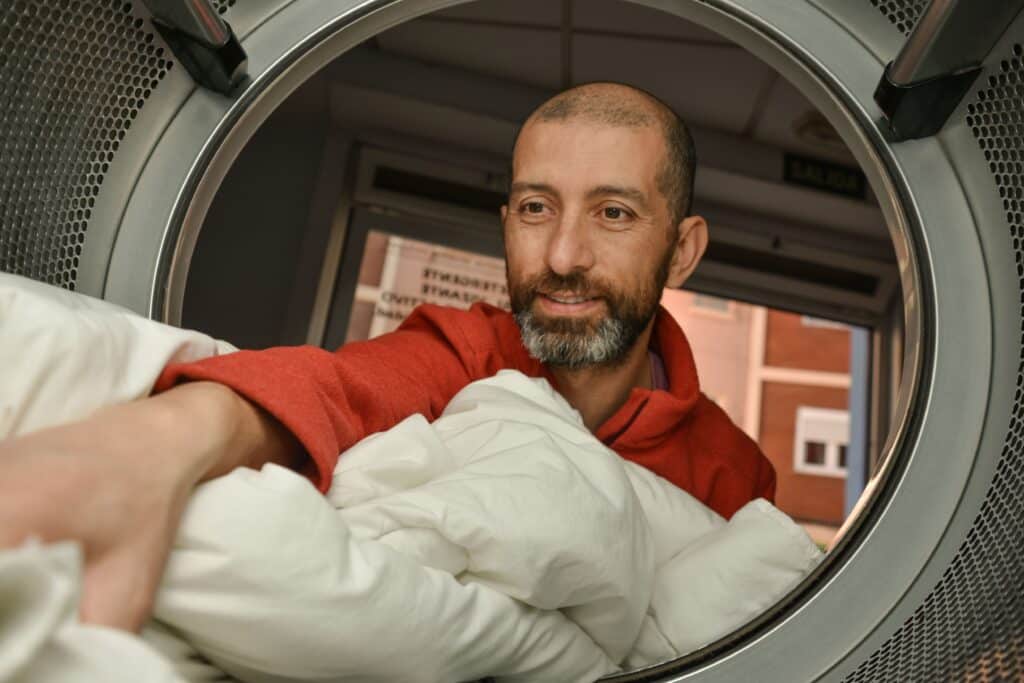 Smiling Man Taking a Duvet out of clothes dryer