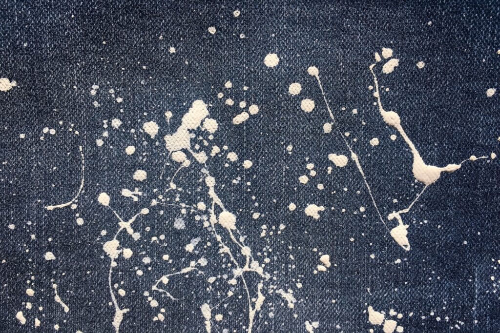 Close-up of a paint splatter stain on the leg of a pair of denim jeans