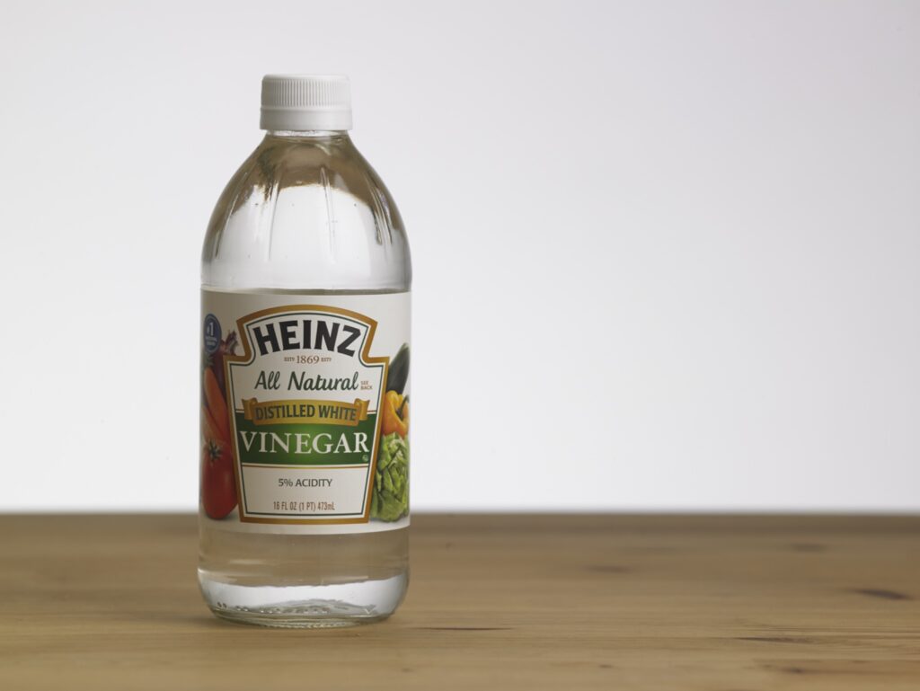 A bottle of Heinz distilled white vinegar placed on a wooden surface