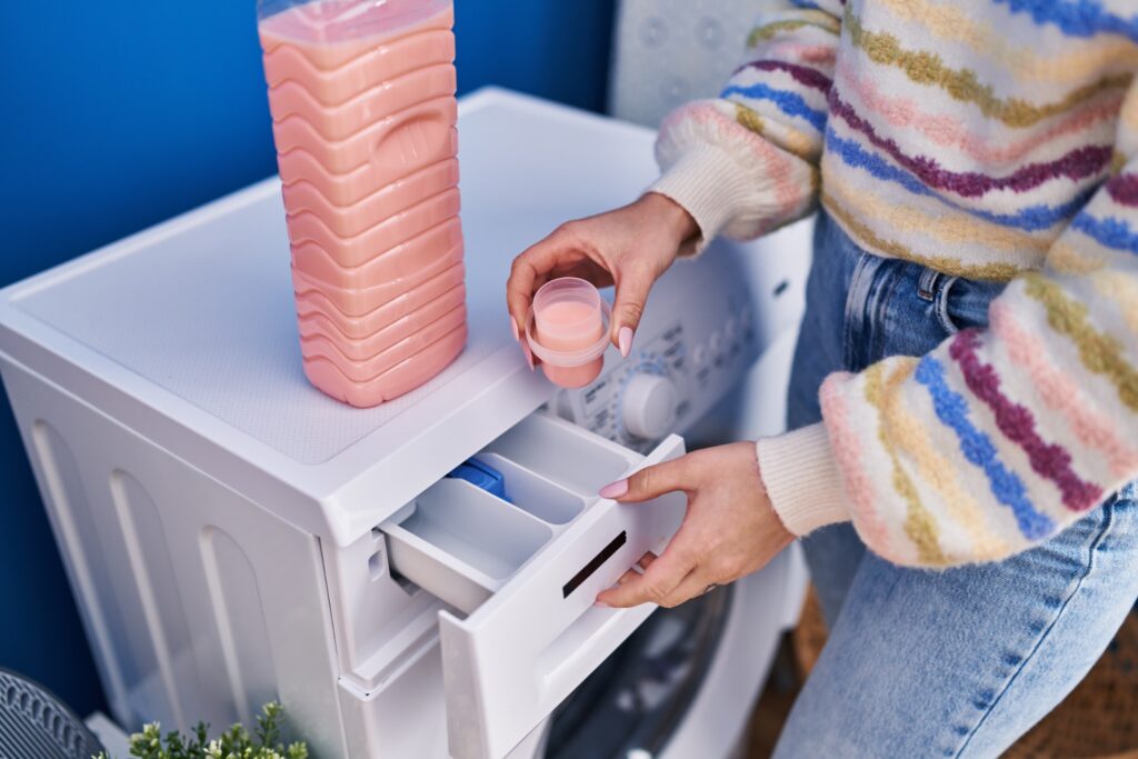 Person placing a dryer sheet into a laundry machine drawer