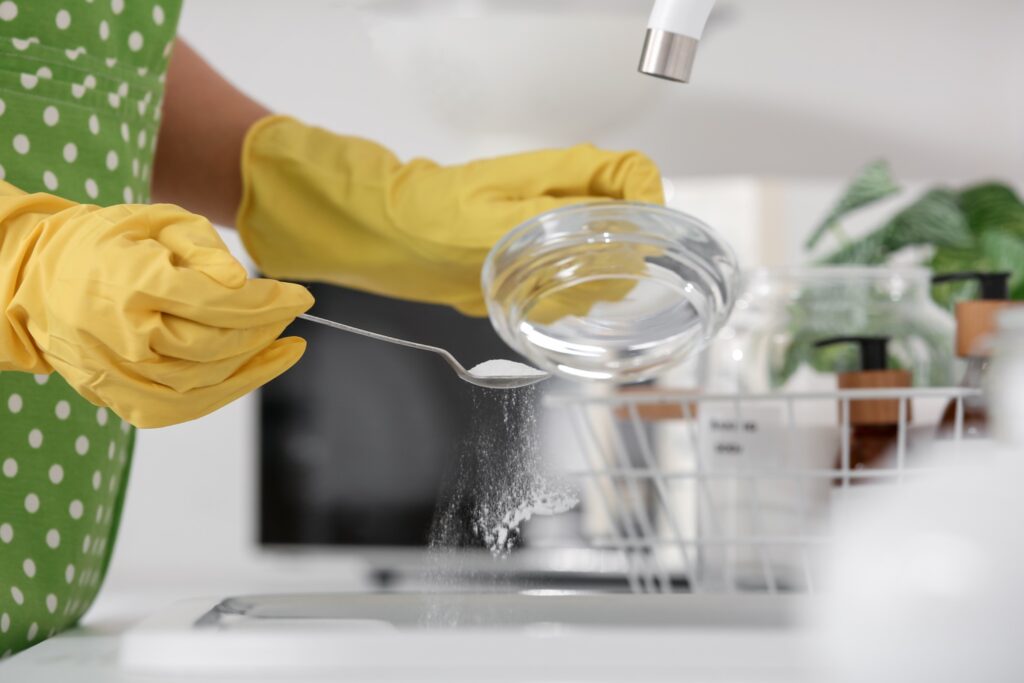  Gloved hands measuring washing soda, emphasizing safe handling and proper use of laundry additives