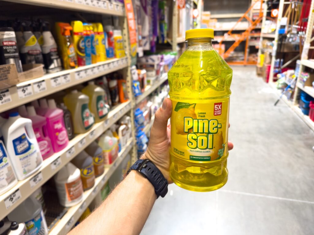 Shopper holding a bottle of Pine-Sol cleaner in a store aisle