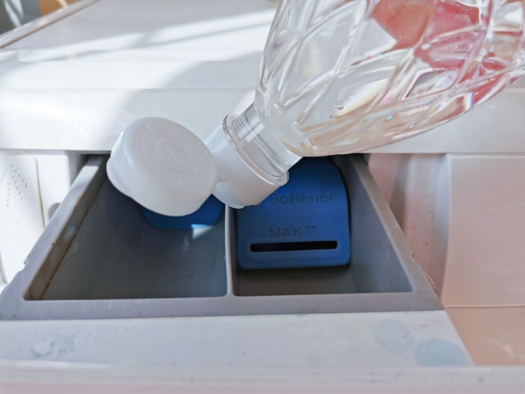 Vinegar being poured into a washing machine fabric softener