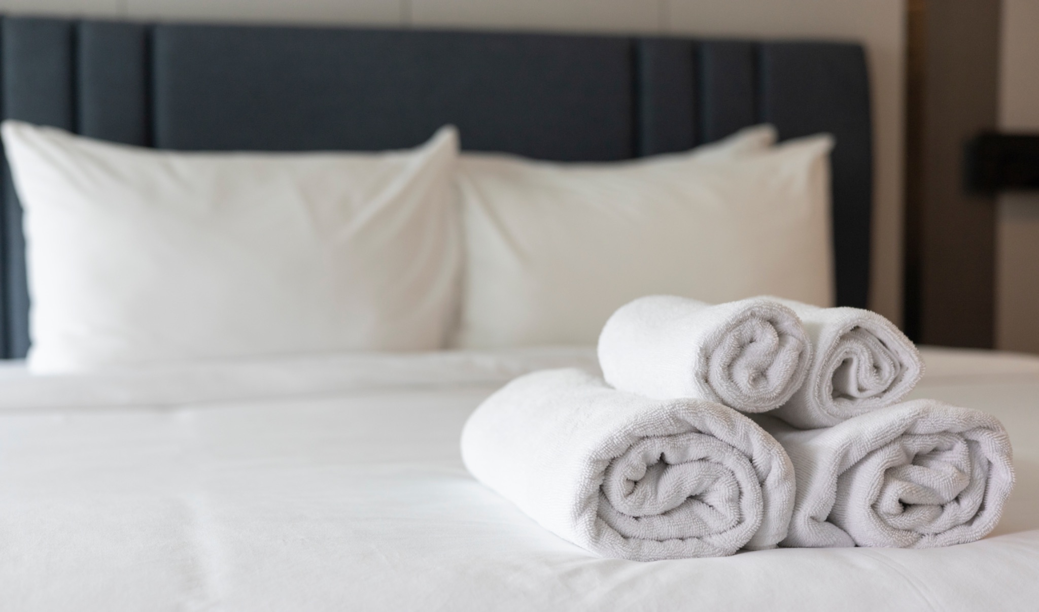 Four white towels on hotel bed