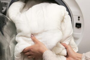 Person Loading White Blanket Into Dryer