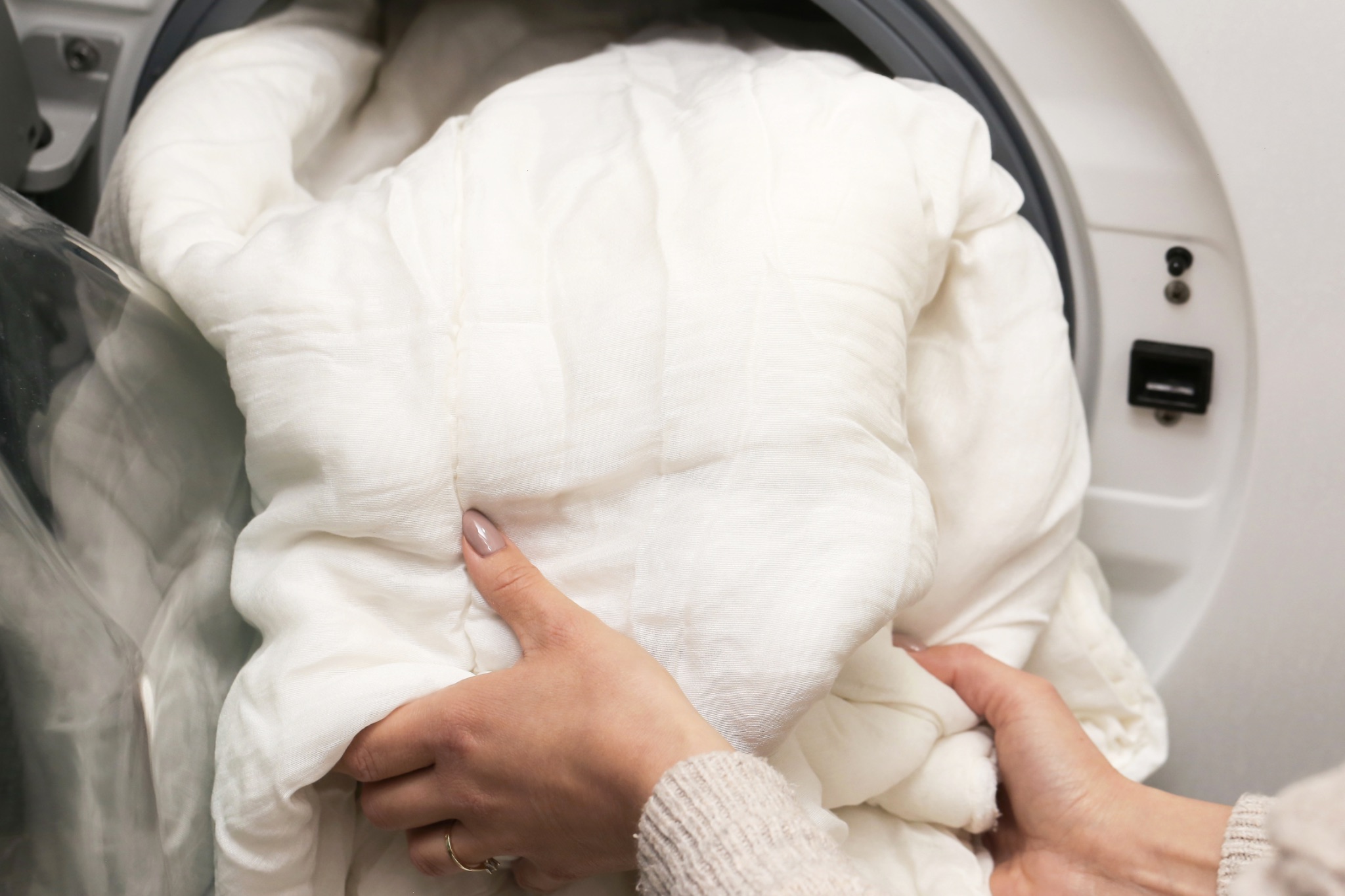 Person Loading White Blanket Into Dryer