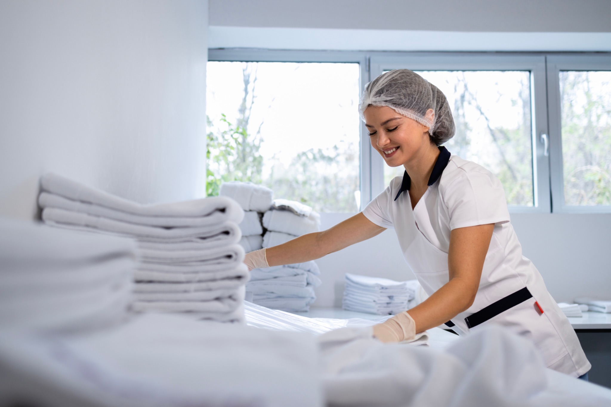 Woman organizing white towels in laundry room