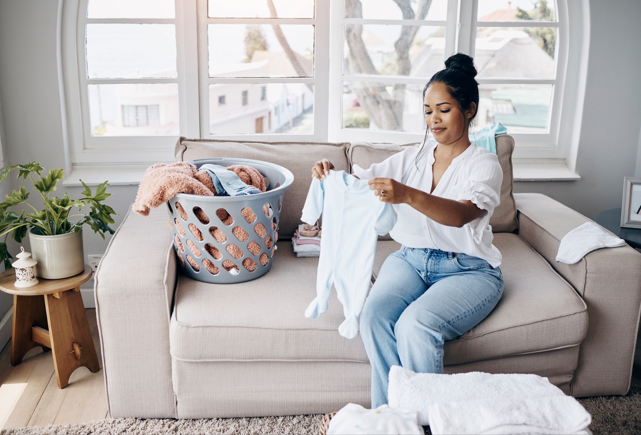 Woman folding baby clothes on sofa