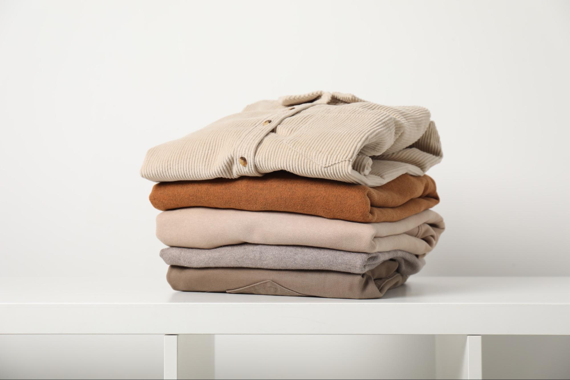 Folded shirts in neutral colors on shelf